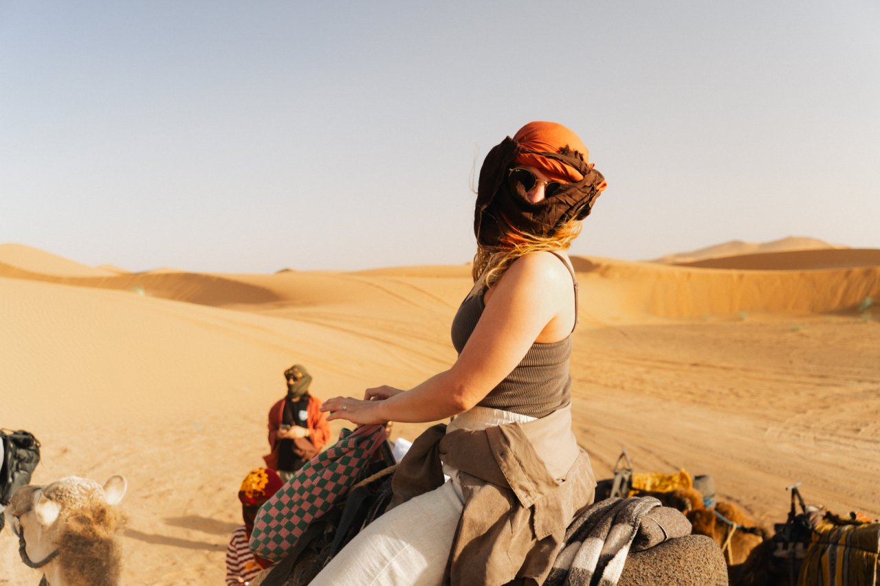 Female traveller in Morocco poses on a sunset camel ride in Morocco